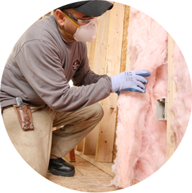 Technician kneeling, adding insulation into open wall