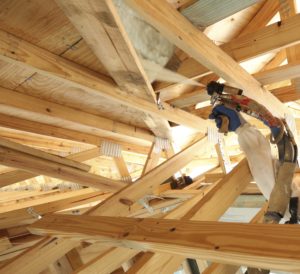 Insulation being installed in an unfinished attic.