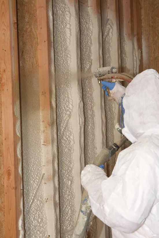 Technician installing spray foam insulation in a wall