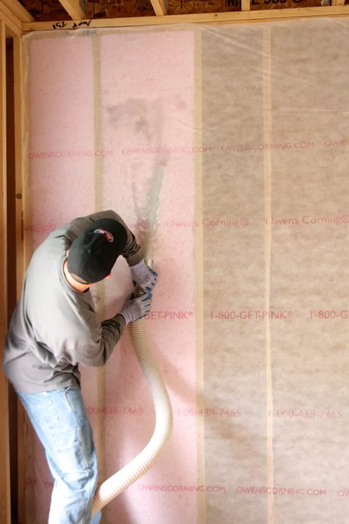 Insulation contractor installing blown insulation in a wall.